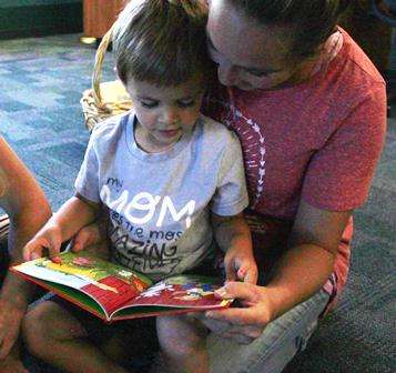 enthusiastic mother reading to preschool child who is on her lap